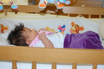 Ligger i spjälsängen.